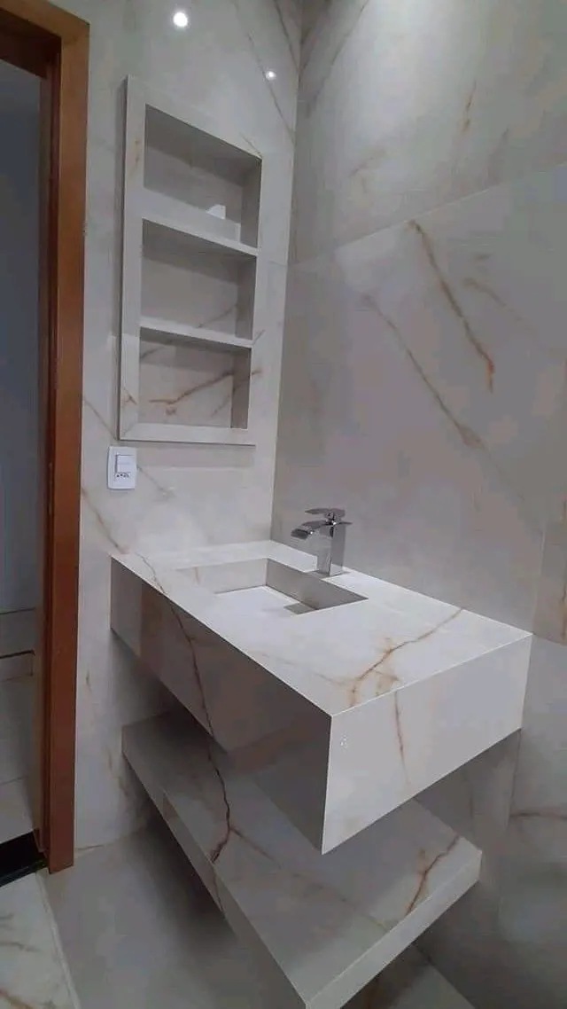 Mueble de baño esculpido en piedra blanca con vetas doradas